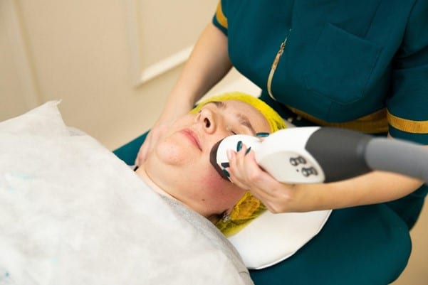 A person lies comfortably on a table at a med spa in Cooper City, receiving a rejuvenating facial treatment. A skilled technician expertly applies an advanced anti-aging skincare device to the person's face, promoting youthful and radiant skin.