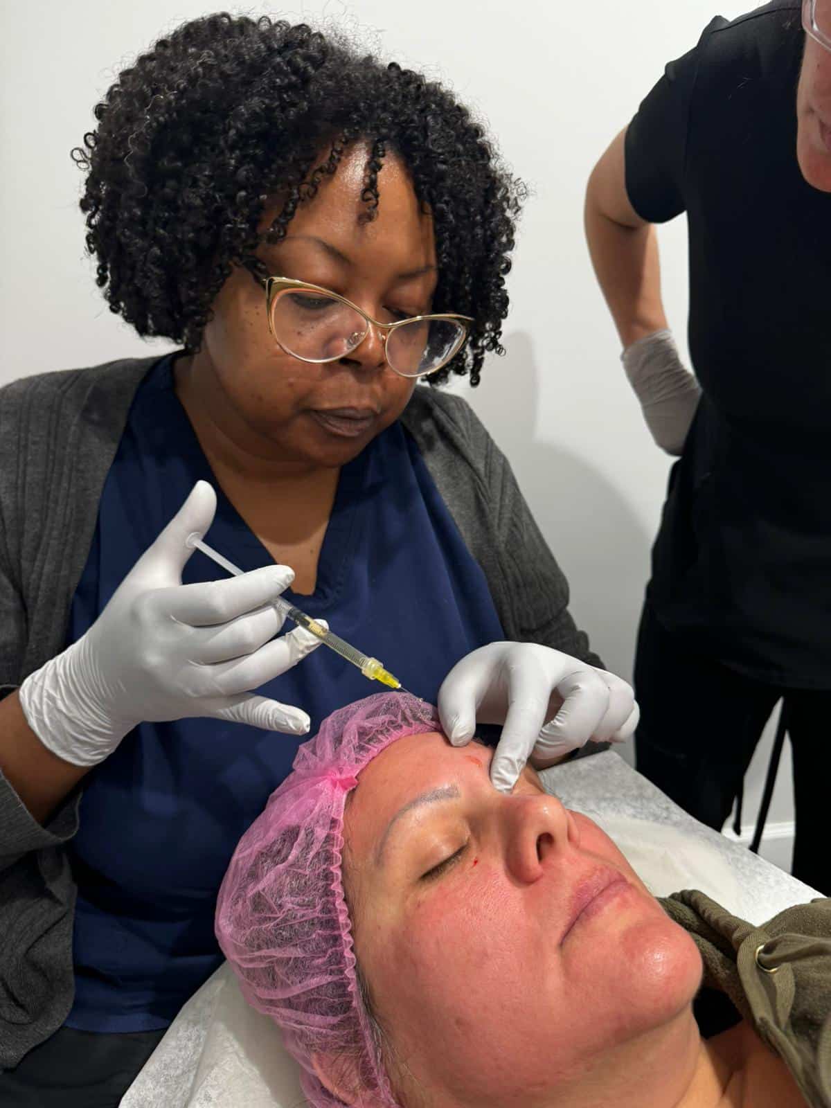 In a med spa located in Cooper City, a healthcare professional carefully administers an injection to a patient's forehead, delivering essential skincare and wellness services. Meanwhile, another trained professional stands nearby, ready to assist and ensure the highest standard of care.